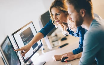 A woman and a man looking concentrated at a screen in the office