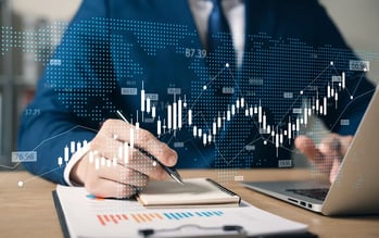 Image showing bars and graphs and a man holding a pen in front of a laptop